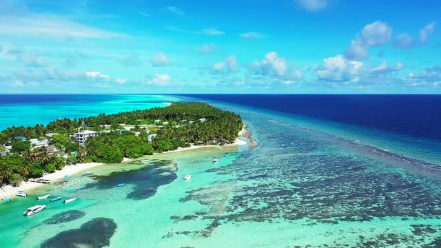 Drone footage of a splendid azure bay in an island  resort on the reef in the Caribbean, with transparent waters, white sand beach and boats waiting for tourists
