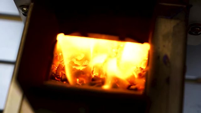 Slow motion hand held shot of a yellow flame firing out he back of a table top pizza oven, flame coming out of a grill,