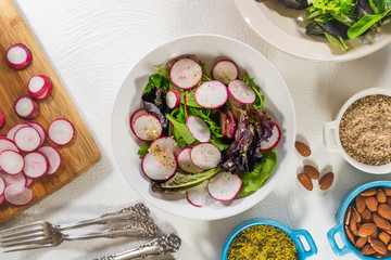 Herb Salad Mix with Radish, Almonds and Seasoning Close Up on a Kitchen Table