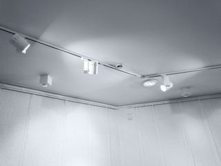perspective view of empty gallery interior wall with row of ceiling spotlights