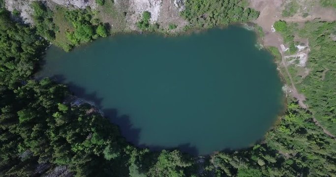Drone flying down towards Gypsum Mine Lake near Cheticamp in Nova Scotia in Canada during the day