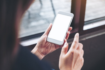 Mockup image of a woman holding white mobile phone with blank desktop screen in cafe