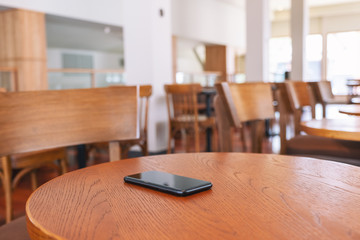 A single black mobile phone on the wooden table