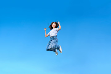 Fototapeta na wymiar 青空を背景にジャンプする女性。幸せ、飛躍、未来イメージ