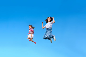 Fototapeta na wymiar 青空を背景に一緒にジャンプする親子。 絆、愛情、幸せ、飛躍、未来イメージ