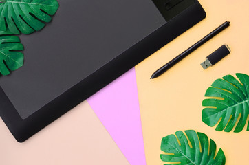 Graphic tablet and pen, memory card and monstera leafs