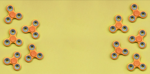 Many orange fidget spinners lies on texture background of fashion pastel orange color paper