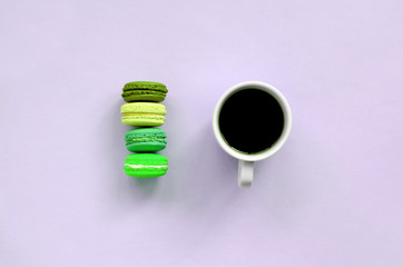 Colorful dessert cake macaron or macaroon and coffee cup on trendy pastel lilac background top view