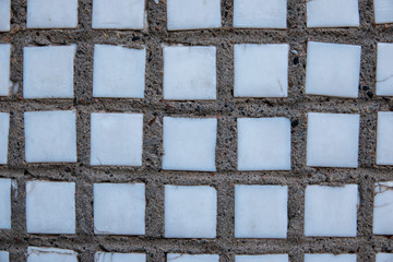 Ceramic squares in concrete. Mosaic white color, joints of gray mortar with stones.