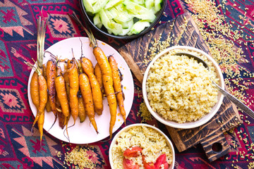 Rich vegetarian, vegan lunch or dinner with baked carrots, vegetables salad and cooked bulgur grain in bowls in Arabic Asian style.