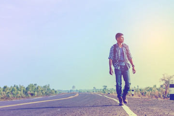 Obraz premium young man looking for freedom lifestyle ; man walking on the road to travel in countryside