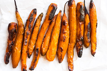 Baked orange sweet carrots on white background.