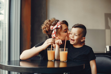Family in a cafe. Mother in a black t-shirt. Cute little boy drinking a juice