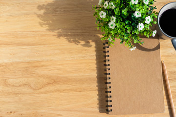 notebook,flower pot tree,a pencil and coffee cup on wooden background,Top view with copy space office table.