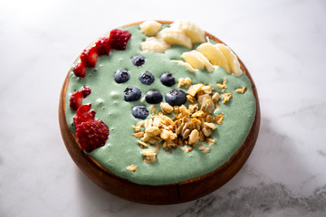 Spirulina yogurt with fruit in wooden bowl