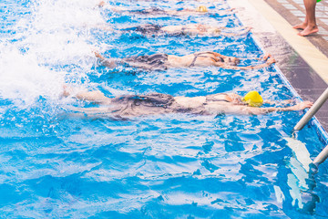 leg shot of girl learning to swim in swimming pool. group of happy girl at swimming pool class learning to swim