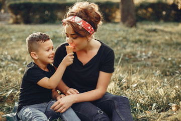 Family in a summer park. Mother in a black t-shirt. Cute little boy with ice cream