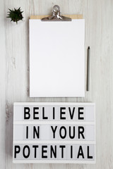 'Believe in your potential' words on a modern board, clipboard with blank sheet of paper on a white...