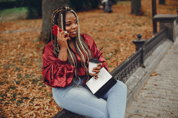 Cute black woman have fun in a city. Beautiful black girl in a red blouse. Woman with coffee. Lady with a phone