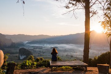 Naklejka na ściany i meble Young woman watching sunrise high in the mountain at Phu Lung ka,Thailand