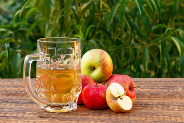 Glass goblet of apple cider and harvested apples on wooden board