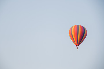 Fototapeta na wymiar Colorful hot air balloon moving up in blue sky.