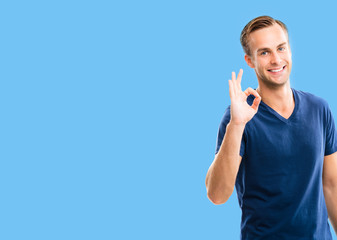 Photo of man showing okay hand sign gesture, over blue background, with copy space for some text or...