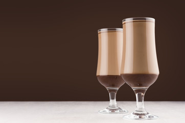 Chocolate and coffee dessert in two elegant transparent glass  in modern dark brown kitchen interior, copy space.