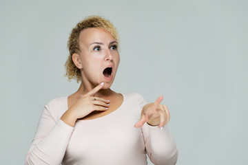 Photo portrait of a beautiful girl blonde woman with short curly hair on a white background talking and showing a lot of emotions. An experienced model shows hands. Beauty.