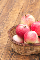 Red apples in wicker basket on wooden boards