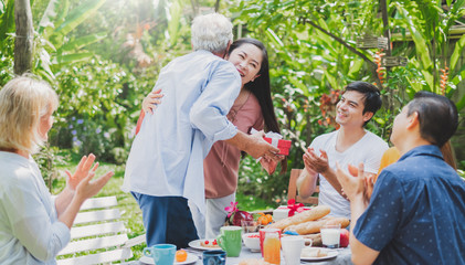 Mix aged big family enjoy having outdoor birthday party eating food at backyard home, warm and happy lifestyle family concept