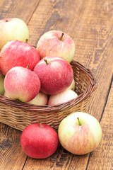 Red apples in wicker basket on wooden boards