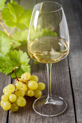 White wine in a glass and a bunch of grapes