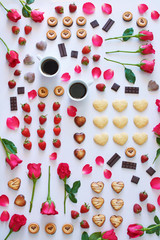 Top view of heart shaped chocolate and cookies, roses, strawberry and coffee over white background. St Valentines or Women day concept. 