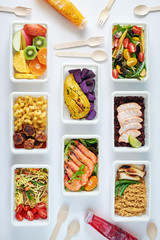Top view of assorted ready meals over white background. Prawns, salmon with brown rice, asian noodles, pasta and meatballs, chicken and potato, mushrooms, vegetable and fruit salad. Healthy eating. 