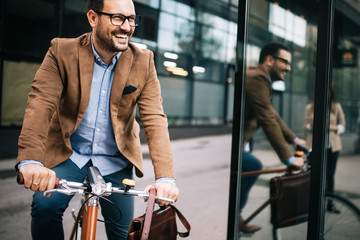 Happy businessman riding bicycle to work in morning