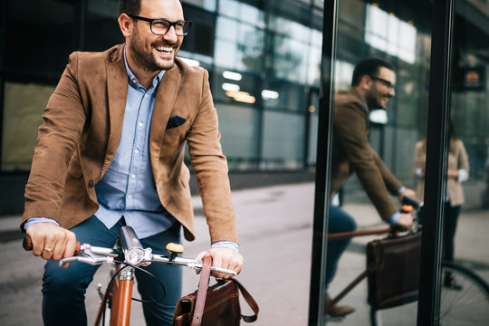 Happy Businessman Riding Bicycle To Work In Morning