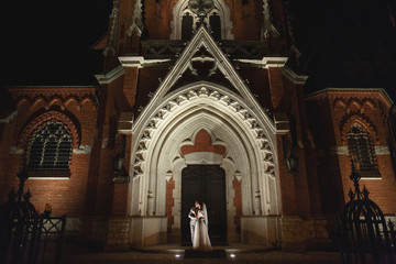 Night photosession of wedding couple in Krakow. Newlyweds walk around the church