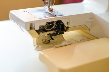 Sewing machine. Work by the light of the built-in hardware lamp. Steel needle with looper and presser foot close-up.