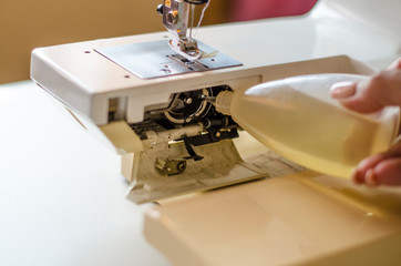 Sewing machine. Work by the light of the built-in hardware lamp. Steel needle with looper and presser foot close-up.