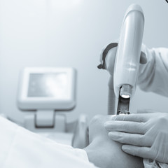 Doctor in protective glasses doing laser removal procedure black white image with a blue toning