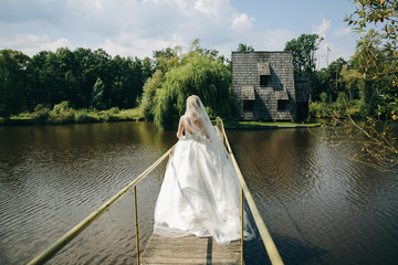 Beautiful bride is walking on the bridge. Wedding photo outdoors.