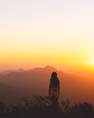 woman silhouette on mountain at sunset