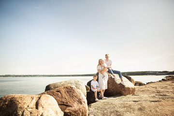 Portrait of a young family with two children, sitting at the pier, The mother holds the daughter in her arms. Estonia, Tallinn