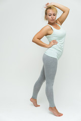 Full-length portrait of a slim beautiful pretty girl blonde woman with short curly hair on a white background in light lingerie standing right in various poses shows fitness and a lot of emotions.