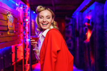 Fototapeta premium Photo of blonde girl with cocktail in her hand on red and blue background