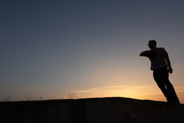 silhouette of man throwing hat at sunset