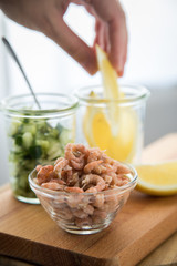 Frau isst Norddeutsche Friesische Nordseekrabben in Glas Schale mit Gurkensalat und Zitronen 