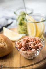 Norddeutsche Friesische Nordseekrabben in Glas Schale mit Brötchen, Gurkensalat und Zitronen auf Holz Brett