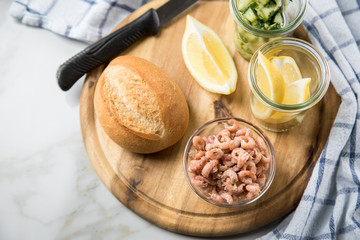 Norddeutsche Friesische Nordseekrabben in Glas Schale mit Brötchen, Gurkensalat und Zitronen auf Holz Brett